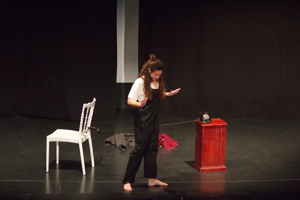 Alba, descalza, interpreta a Dora Maar junto a una silla blanca y un teléfono.
